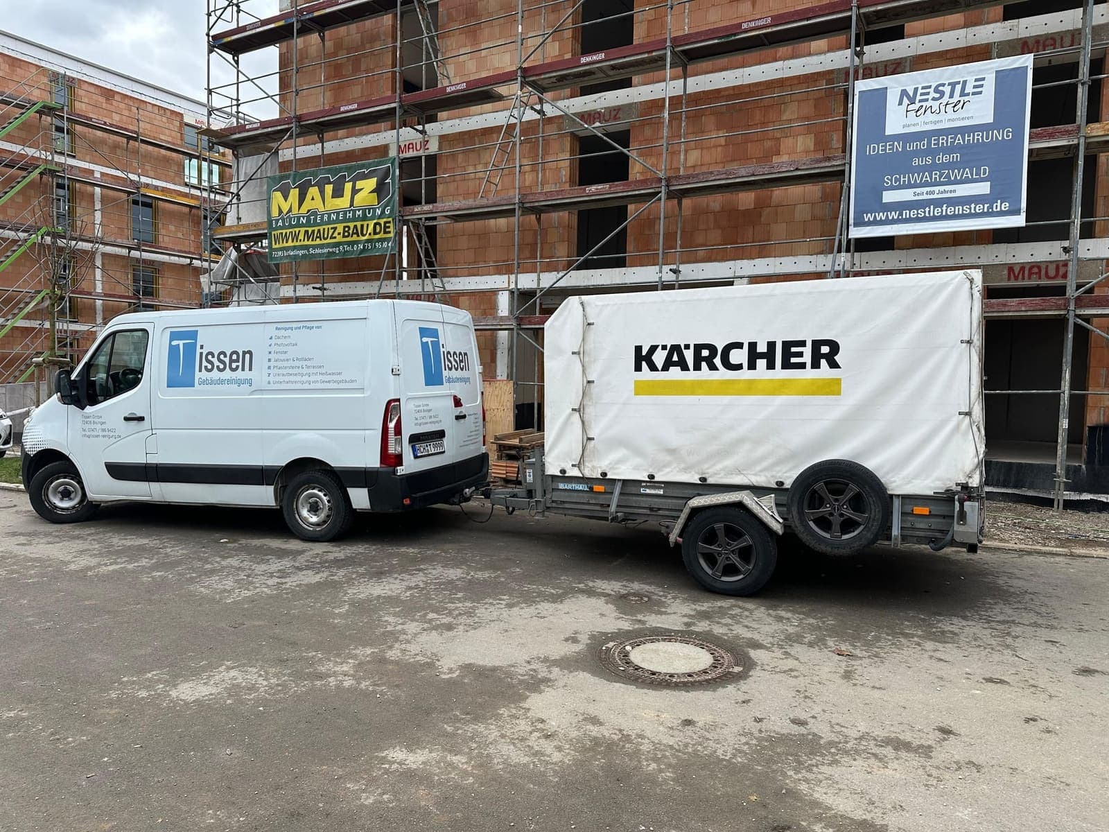 Tissen-Transporter mit Kärcher-Profi-Anhänger vor Baustellen-Gerüst